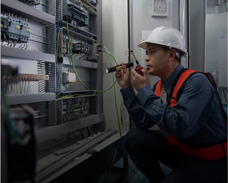 Technician inspecting electrical panel with tools.