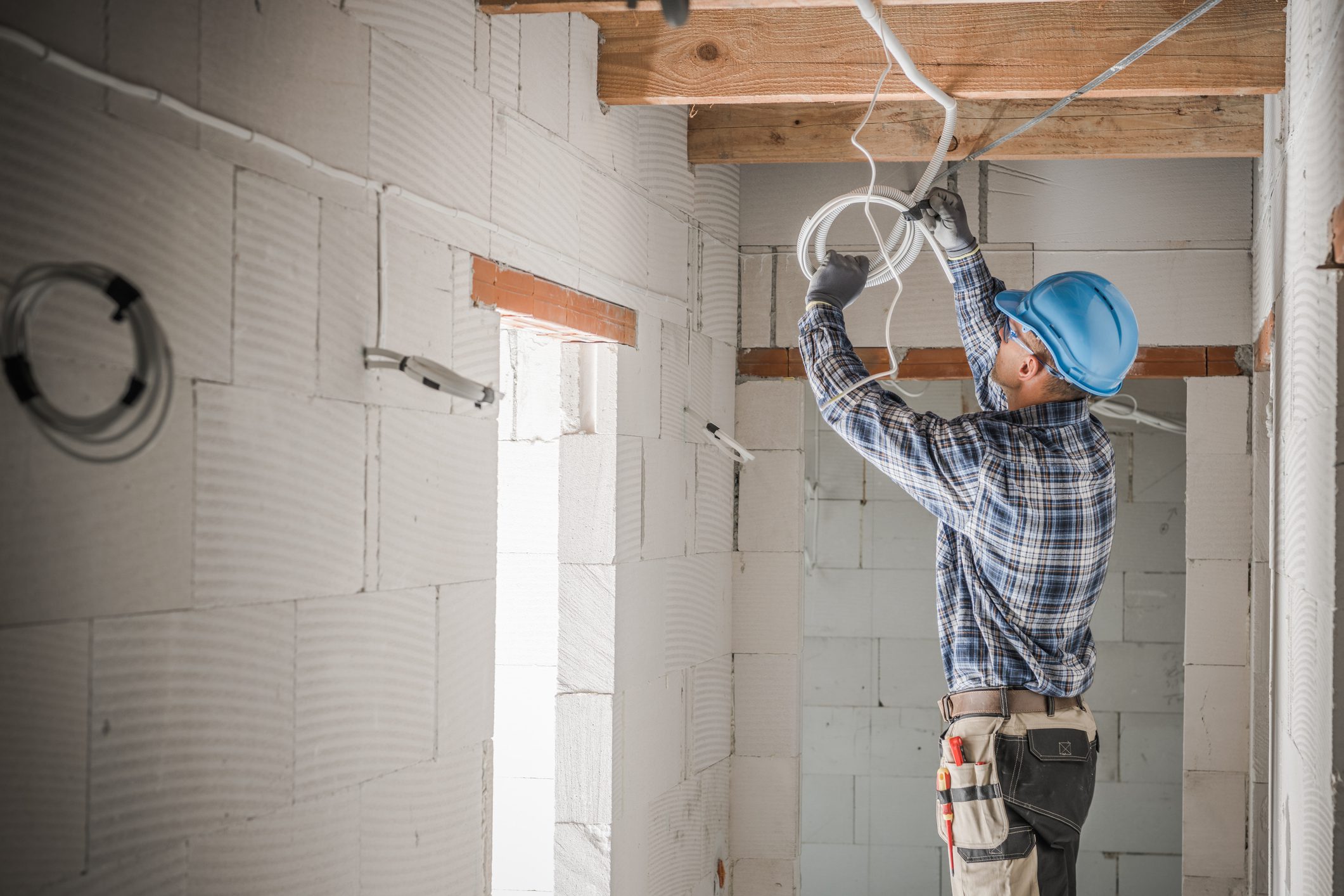 Electrician working on ceiling wiring installation.