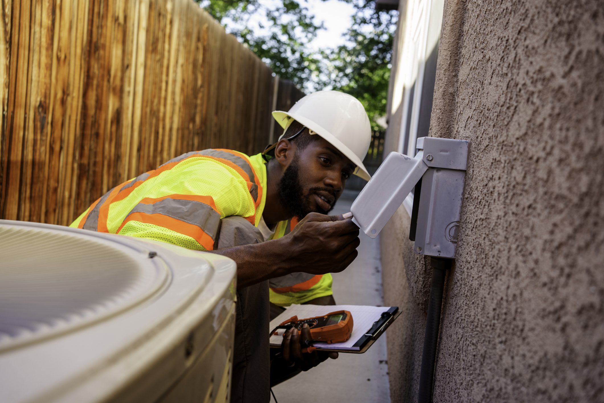 Worker inspecting electrical panel outdoors.