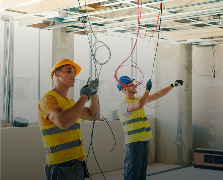 Electricians working on ceiling wiring installation.